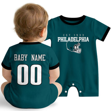 Baby wearing Philadelphia football-inspired personalized romper in midnight green, featuring custom name and number design with sporty varsity lettering and football helmet graphic